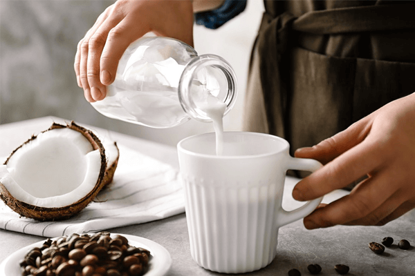 اضافه کردن شیر به لیوان در کنار یک نارگیل نصفه